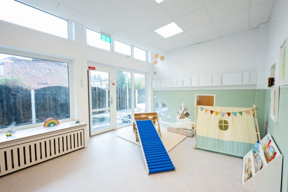 Spielzimmer mit einer Rutsche, einem Bereich zum Spielen und bunten Wanddekorationen.