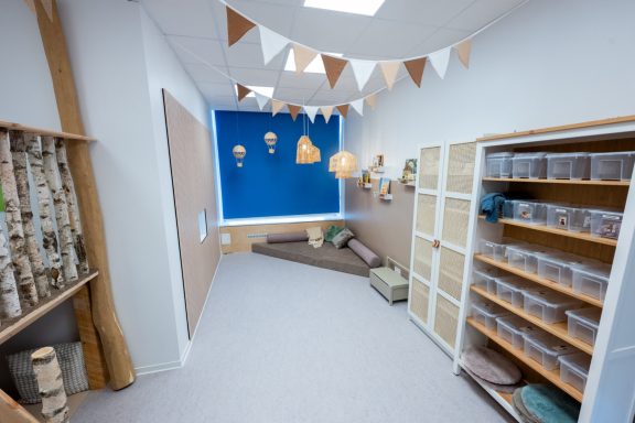 Blick in einen hellen Raum mit bunten Dekorationen und Kisten zur Aufbewahrung.