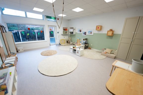 Lichtdurchfluteter Raum mit Teppichen, Spielzeug und einer ruhigen Lernumgebung.